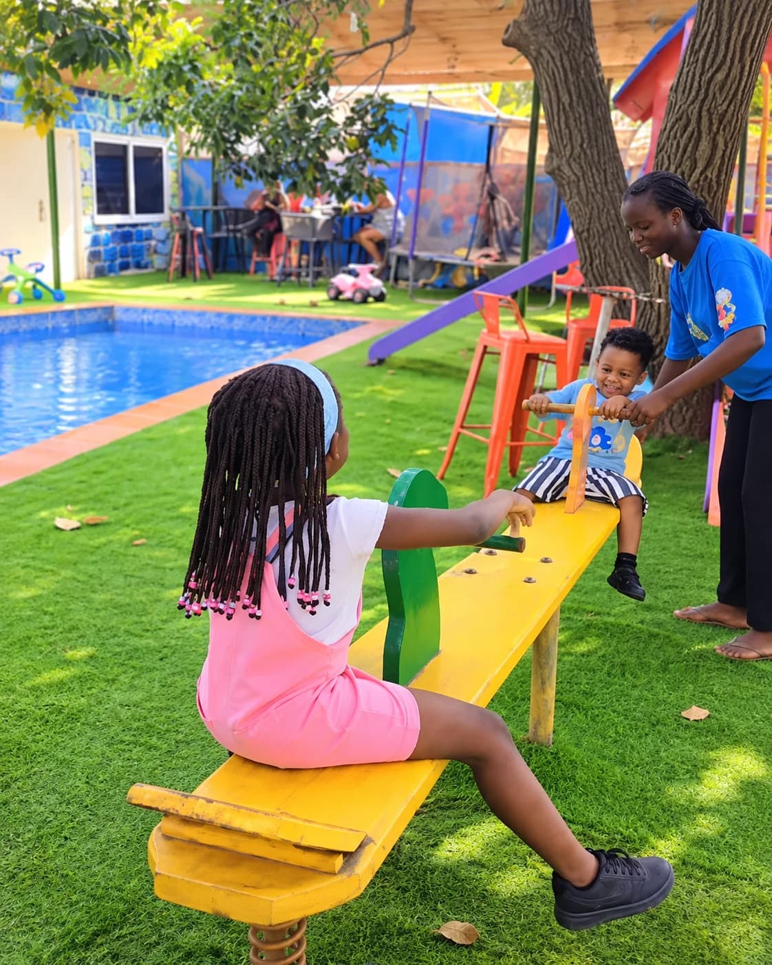 Children enjoying the seesaw beside the playground pool